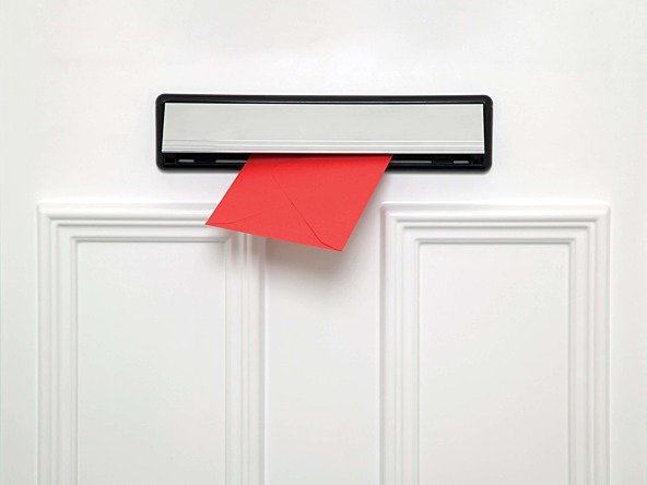 Red envelope being posted through a white door with a silver letterbox